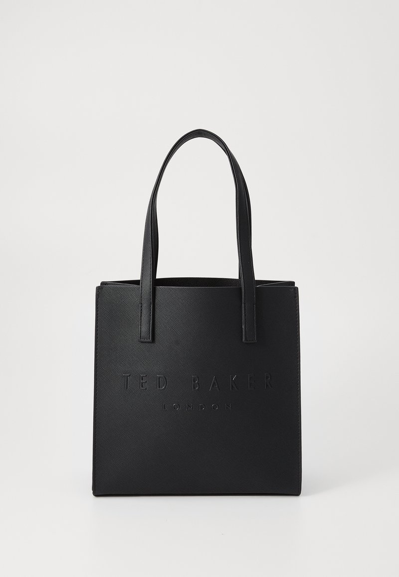 Musta käsilaukku, jossa on teksturoitu synteettinen materiaali, kohokuvioitu logo edessä ja kaksi vahvaa litteää kahvaa. Neliön muotoinen avonaisella ylhäällä.