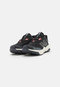 Zwarte sportieve schoenen met een bovenwerk van mesh, contrasterende koraalkleurige accenten, een gestructureerde rubberen zool met spikkels en een logo aan de zijkant.