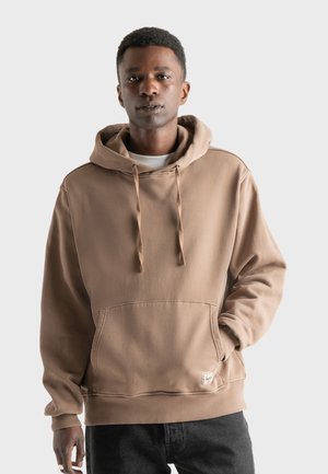 Brown cotton hoodie with a drawstring hood, front kangaroo pocket, and ribbed cuffs. Features a subtle logo patch on the hem.