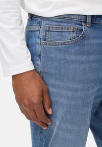 Blauwe denim jeans met een gladde textuur, vijf-pocket ontwerp, contrasterende stiksels en een slim fit, getoond met een witte lange mouw shirt.