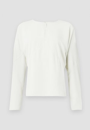 Valge pika varrukaga topp ümmarguse dekolteega ja taga lukuga. Omab vabalt langetatud lõiget ning peeneid õmbluse detaile, valmistatud siledast kangast.