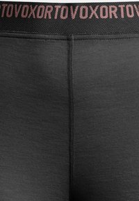 Black leggings with a smooth texture, featuring a wide elastic waistband with pink lettering. The design includes a central seam at the back.
