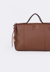 Borsa a mano in pelle marrone con superficie texture, caratterizzata da un dettaglio di manico intrecciato, minuteria dorata e un accento con logo sul davanti.