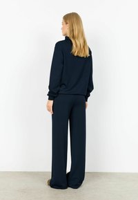 Set de lounge albastru marin format dintr-un pulover cu croială lejeră și pantaloni cu picioare largi. Material texturat moale, cu manșete la mâneci și talie.