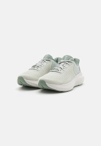 Světlé zelené sportovní boty s prodyšným síťovinovým svrškem, texturovanými překrytími a měkkou bílou podrážkou. Viditelné šňůrky a logo.