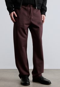 Pantaloni de trening bordo, cu croială lejeră, având talie elastică, șnur ajustabil și logo în relief pe coapsa stângă.