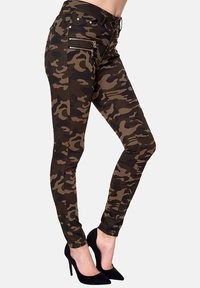 Camouflage Skinny-Jeans in Braun- und Grüntönen, ausgestattet mit Reißverschlusstaschen und einem schlanken, eng anliegenden Design. Akzentuiert mit schwarzem Stich.