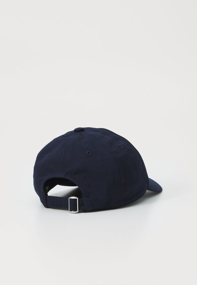 Navyblauwe pet van katoen, met een gebogen rand, verstelbare band met metalen hardware en een genaaide oogje aan de bovenkant.