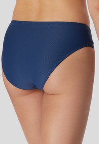 Navyblaue Bikinislip aus strukturiertem Stoff, mit hohem Beinausschnitt und nahtlosem Bund für Komfort.