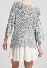 Maglione grigio a maglia, dal fit morbido e con scollo a barca ampio, con maniche a tre quarti e un design testurizzato, abbinato a una gonna bianca a campana.