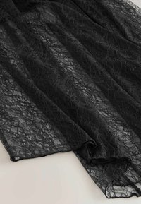 Schwarzer Spitzenstoff mit floralem Muster, der eine zarte, strukturierte Oberfläche aufweist. Dieses leichte Material fällt weich.