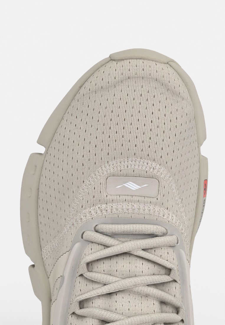 Zapatillas de malla beige con una parte superior texturizada, puntera redonda y sistema de cordones. Presentan un panel gris y un logotipo en el lateral, con acentos en la suela acolchada.