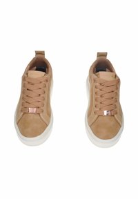 Un paio di sneakers beige con suole bianche, lacci larghi e dettaglio metallico sulla parte anteriore, viste dall'alto su uno sfondo bianco.