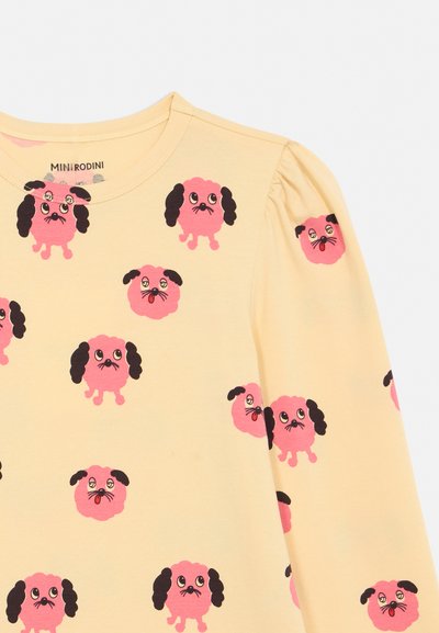 Gelbes Langarmshirt mit pinkfarbenen Cartoon-Hundegesichtern, die schwarze Ohren und ausdrucksstarke Augen zeigen, über den gesamten Stoff gedruckt.