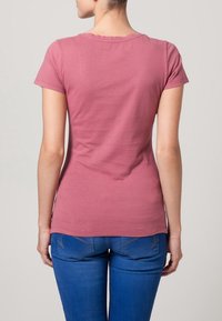 Tightats kortärmad t-shirt i mjuk, rosa bomull med rund halsringning. Bakifrån visas en slät textur och minimala sömmar. Inga mönster eller utsmyckningar.