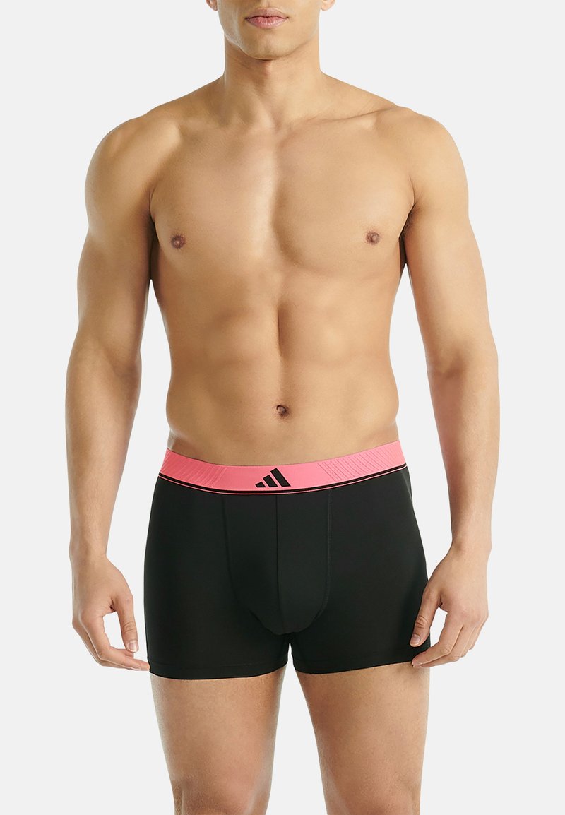 Svarta boxershorts med en rosa midja som har en logotyp och randig design. Tyget ser slätt och åtsittande ut.