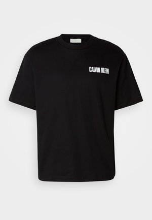 Juodas medvilnės marškinėliai su apvaliu kaklu, trumpomis rankovėmis ir balta "CALVIN KLEIN" logotipu kairiajame krūtinės plote.