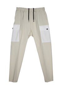 Beige elastische broek met een losse fit, voorzien van witte patchzakken aan de zijkanten, zwarte trekkoorden en knoopaccenten op de zakken.