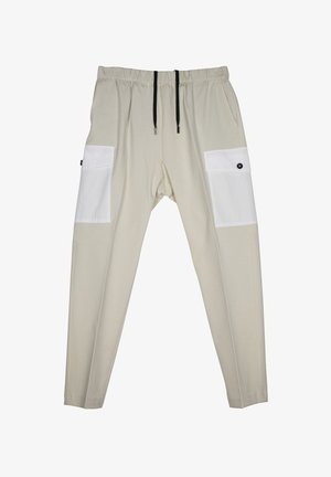 Pantalon beige élastique avec une coupe décontractée, doté de poches latérales blanches, de cordons noirs et d'accents de bouton sur les poches.