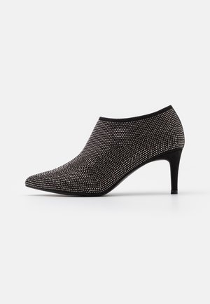 Schwarze Stiefeletten mit Absatz und spitzem Zeh, aus einem strukturierten Stoff mit metallischen Nieten verziert; schlanker Stiletto-Absatz.
