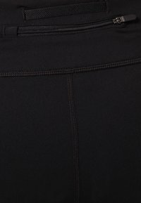 Leggings sportivi neri realizzati in un tessuto liscio e elasticizzato, con cuciture piatte e una tasca con zip sicura sulla vita posteriore.