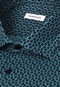 Chemise à col avec petit motif floral bleu sarcelle et noir et boutons noirs, affichant une étiquette blanche avec le texte "seidensticker."