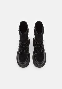 Zwarte enkellaarsjes met een bovenwerk van suede, gestructureerde veters en rubberen zolen. Voorzien van een ritsluiting en stikseldetails langs de randen.