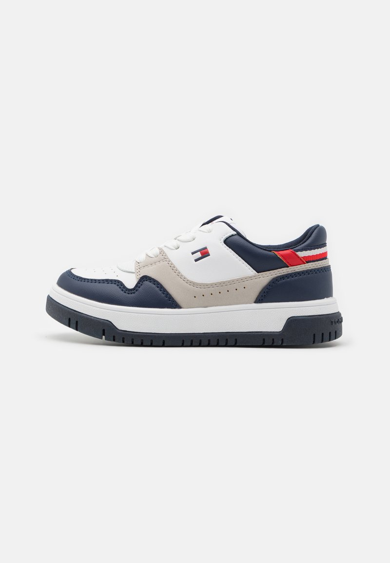 Sneaker bianchi con un design in pelle lucida blu navy e beige, caratterizzati da una striscia accentuata rossa e bianca, punta rotonda e suola in gomma testurizzata.