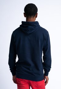 Marineblauwe hoodie gemaakt van zacht materiaal met een trekkoord capuchon en lange mouwen. Voorzien van een geribde zoom en manchetten.