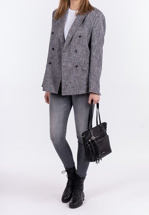 Grau strukturierter, doppelt geknöpfter Blazer, weißes T-Shirt, graue Skinny-Jeans, schwarze Schnürstiefel und eine kleine schwarze Lederhandtasche.