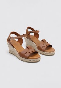 Sandalias de cuña de cuero marrón con tacón de yute trenzado, que cuentan con tiras cruzadas, una correa en el tobillo y una plantilla suave.