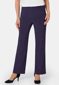 Lila dehnbare Hosen mit einem elastischen Bund, weitem Bein-Design und glatter Textur, kombiniert mit schwarzen High Heels.