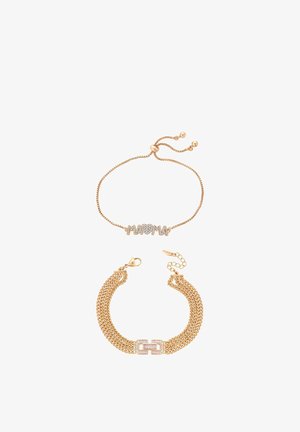 Două brățări aurii: una cu lanț ajustabil și "MOM" din cristale, cealaltă cu un design multi-lanț și o închizătoare acoperită cu cristale.