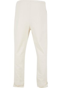 Lyse beige bomullsbukser med elastisk linning, rett ben design, lite tilpasning ved kanten, og ingen synlige lommer eller dekorasjoner.