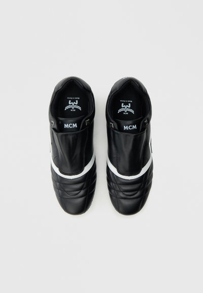 Μαύρα δερμάτινα παπούτσια με λευκή ρίγα διακοσμητική, καπιτονέ υφή στα πλάγια, σχέδιο χωρίς κορδόνια και λογότυπο στο εσωτερικό πέλμα.
