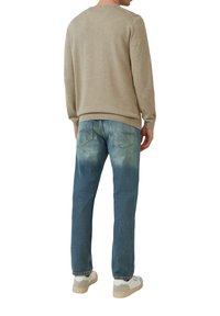 Beige sweater with a crew neck, paired with light blue jeans featuring a faded design and a slight distressed texture. White sneakers complete the look.