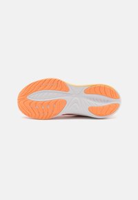 Schuhsohle mit weißem Grund und orangefarbigen Akzenten, strukturierten Mustern für Rutschfestigkeit und fließenden Linien für Flexibilität.