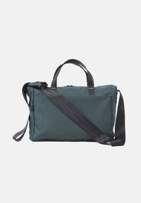Dunkelgrüne Tote-Tasche aus wasserfestem Material, mit zwei oberen Griffen und einem langen, verstellbaren Schulterriemen. Sie verfügt über einen Reißverschluss und ein minimalistisches Design.