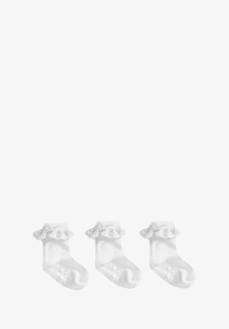 Białe skarpetki bawełniane do kostek z ozdobnymi koronkowymi falbanami na górze oraz silikonowymi kropkami antypoślizgowymi na podeszwach. Wyeksponowane trzy pary.