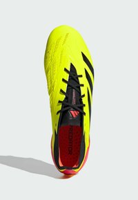 Scarpini da calcio giallo brillante con accenti neri, tomaia testurizzata e interno rosso. Presentano un sistema di chiusura con lacci e motivi di design distintivi.