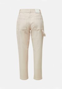 Jasnobeżowe spodnie o prostym kroju, z dwiema kieszeniami z tyłu i jedną kieszenią z boku, wykonane z miękkiego materiału o gładkiej fakturze.