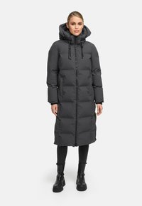 Long dark gray puffer coat with a hood, zip closure, and side pockets. Features a quilted design and is knee-length. Worn over black pants and boots.