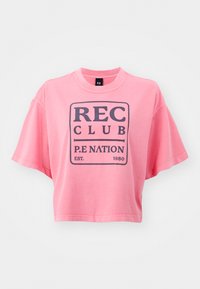 Růžové zkrácené tričko vyrobené z bavlny, s tmavě modrým grafickým textem "REC CLUB P.E NATION EST. 1980" na přední straně, krátké rukávy.
