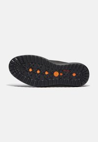 Suela de goma negra con textura y un dibujo, que presenta acentos y un logo en naranja. Diseñada para ofrecer tracción con un patrón resistente para mayor durabilidad.
