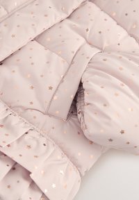 Veste matelassée rose clair avec un motif d'étoiles en rose métallique. Poignets froncés et ourlet à volants ajoutent texture et détails.