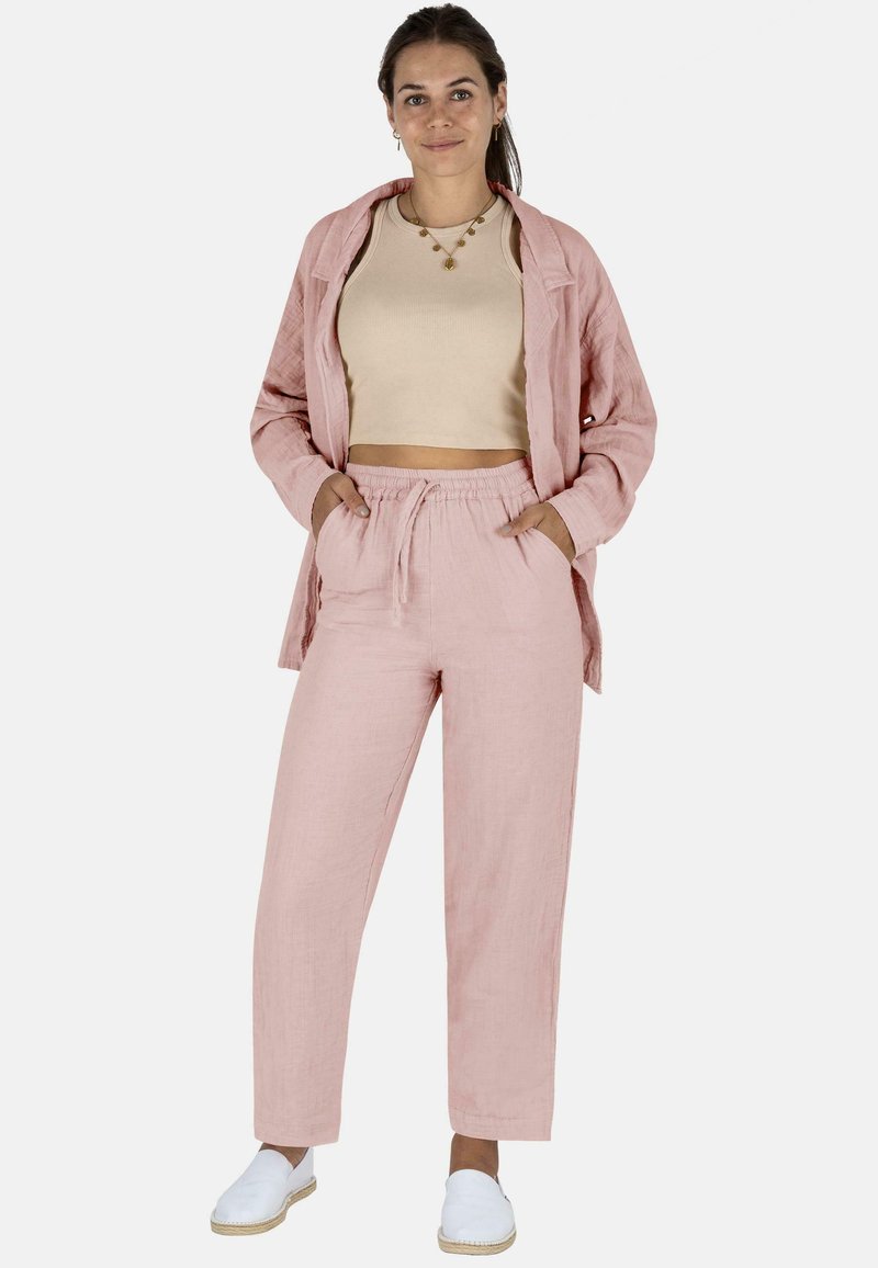 Leichtes rosa Leinen-Outfit, bestehend aus einem lockeren Kurzarmhemd mit Knopfleiste und Jogginghosen mit Kordelzug, kombiniert mit weißen Slippern. Einfaches Design, lässige Passform.