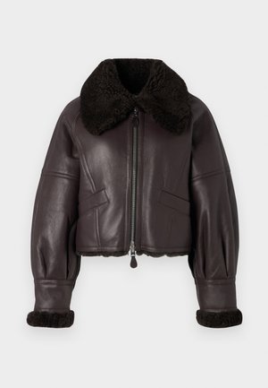 Brun läderkort jacka med en stor mörk shearlingkrage, dragkedjestängning och ribbade shearlingärmar. Har snedställda framfickor.