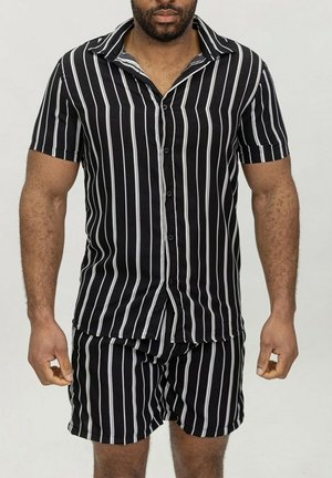 Chemise à rayures noires et blanches à manches courtes avec un col, assortie à un short. Tissu doux avec une fermeture à boutons sur le devant.