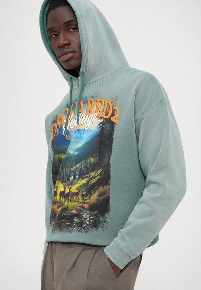 Hooded majica u svijetlozelenoj mješavini pamuka, s prednjim grafičkim prikazom slikovitog planinskog pejzaža s jelenima i logotipom u narančastoj i bijeloj boji.
