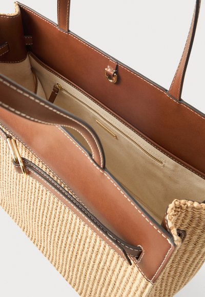 Τσάντα tote από καφέ δέρμα και πλεκτό καλάμι που δείχνει την εσωτερική φόδρα από μπεζ ύφασμα και τσέπη με φερμουάρ με χρυσό φερμουάρ.